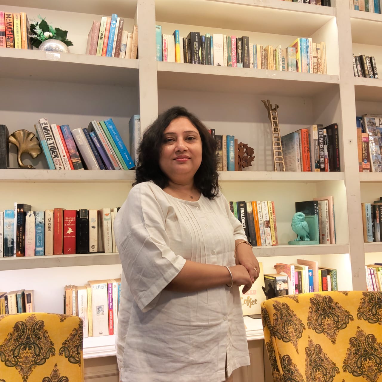 Paramitta standing beside a bookshelf